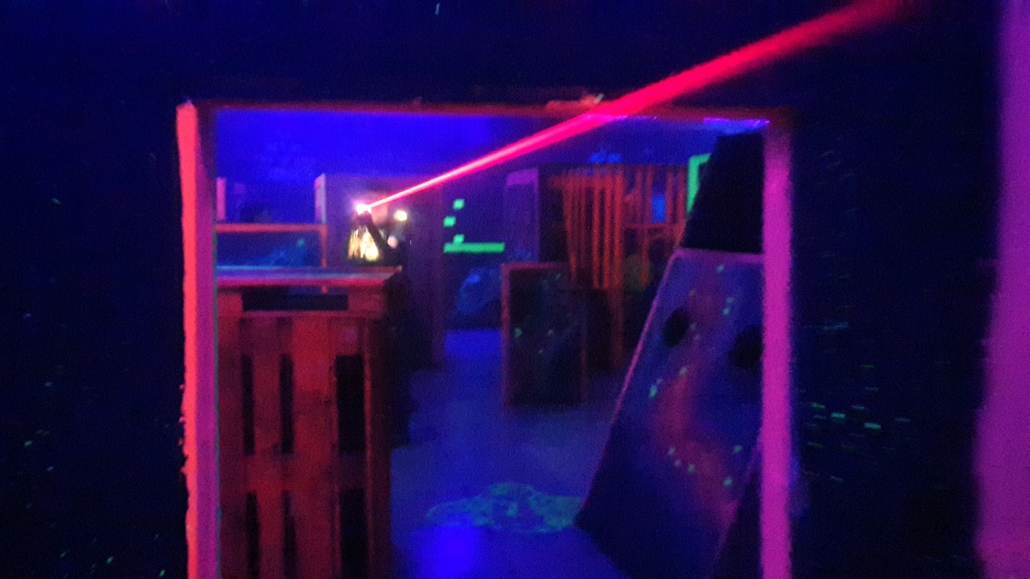 Dunkler Raum mit Holzkisten und einem roten Laserstrahl, der durch die Mitte verläuft.